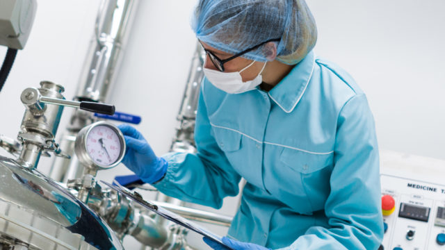Man stood in PPE Equipment next to machine