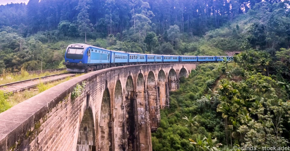 Train moving across rails with scenic background